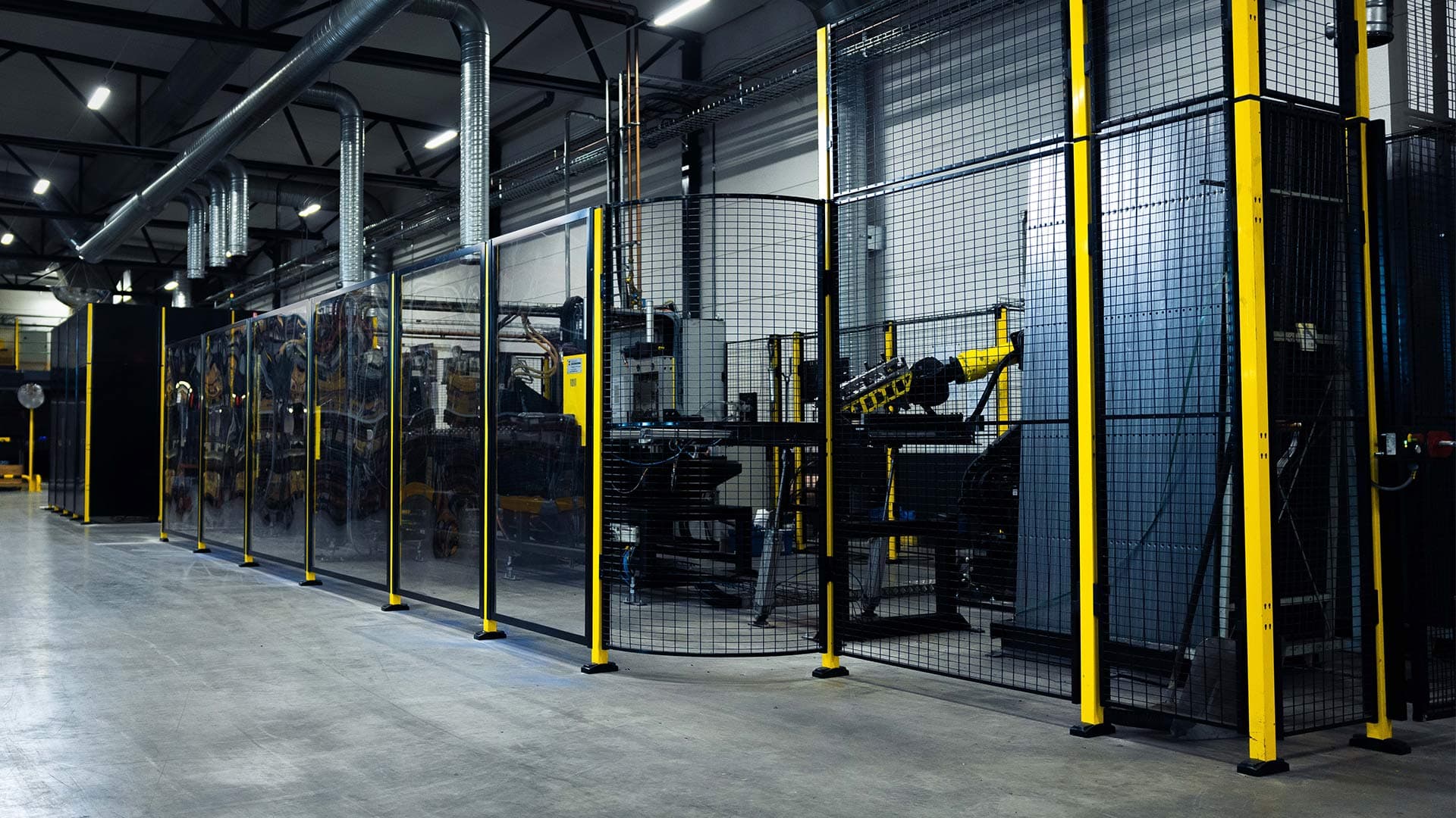 An industrial facility with protective guard fencing and integrated safety switches, enclosing robotic machinery. The image highlights the importance of selecting the right safety switches to control access and ensure worker protection in automated environments.