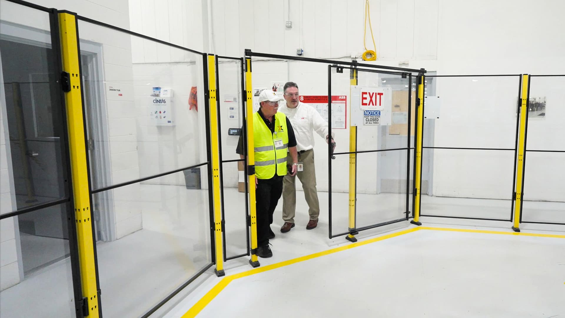 Jeno Kasa of ABB Robotics is shown opening a machine guarding door partnered with an Axelent representative