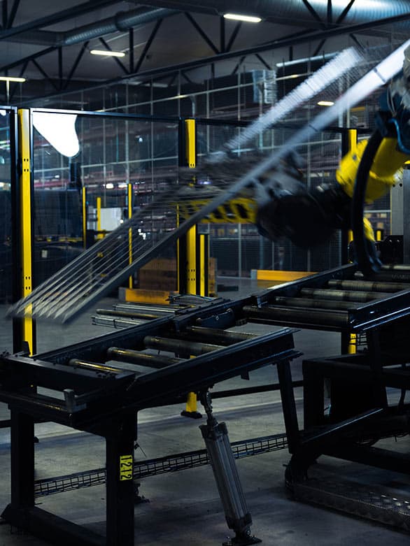 An industrial robotic arm in motion, handling metal components in a high-speed production environment. The image highlights the critical need for emergency stop switches to quickly halt machinery in case of malfunctions or safety hazards.